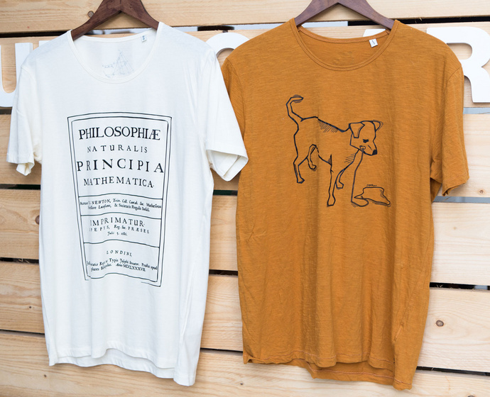 Zwei T-Shirts mit verschiedenen Motiven hängen an der Wand