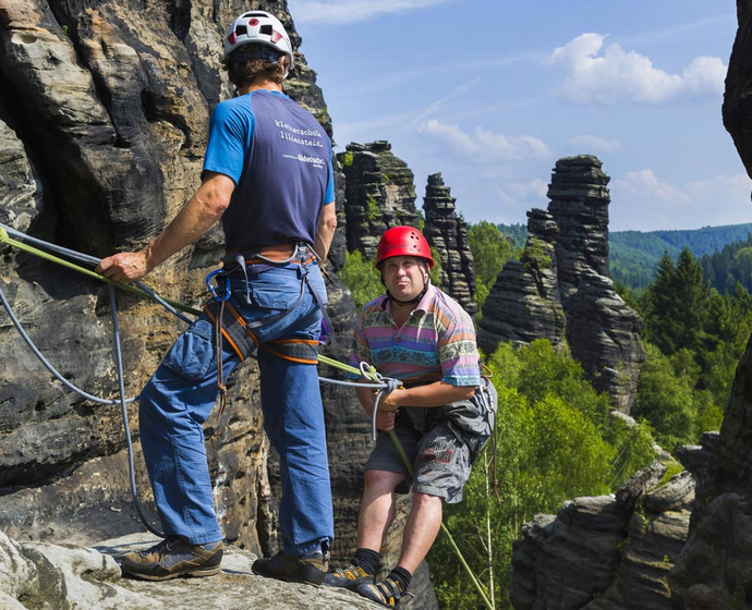 Kursteilnehmer und Kletterlehrer beim Abseilen