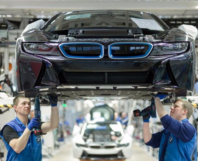 [Translate to Englisch:] Techniker schrauben den Unterboden eines BMW-i-Modells zusammen 